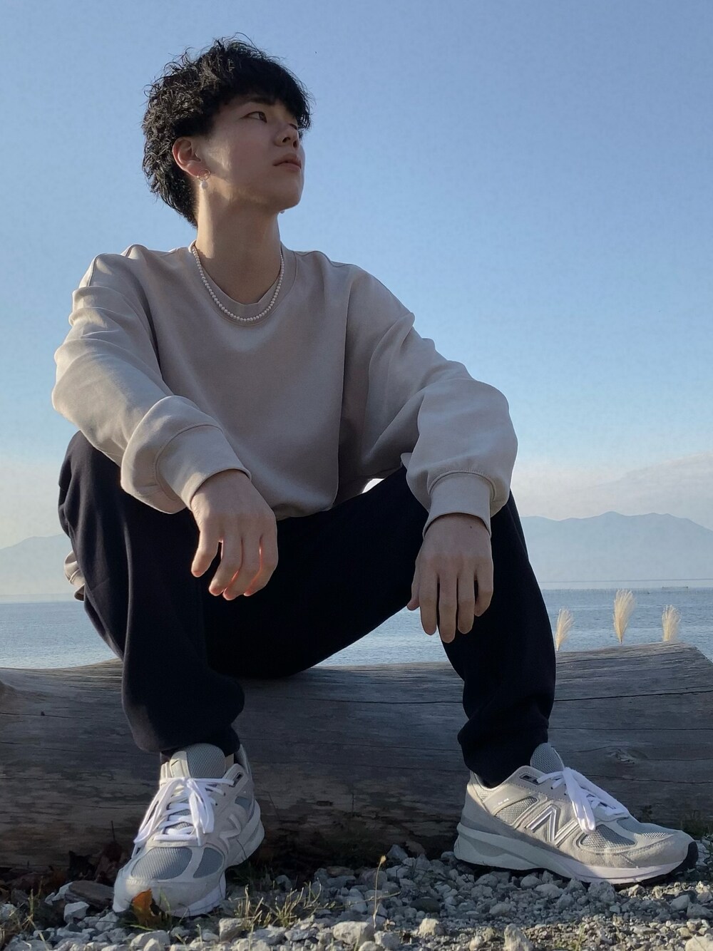 ブラック系のスウェットパンツ、ベージュ系のスウェット、グレー系のスニーカーを着用したメンズの冬コーディネートの1枚目の写真