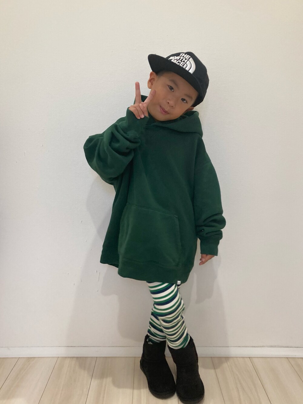 グリーン系のパーカー、ブラック系のキャップ、ブルー系のレギンス/スパッツを着用したキッズの秋コーディネートの1枚目の写真