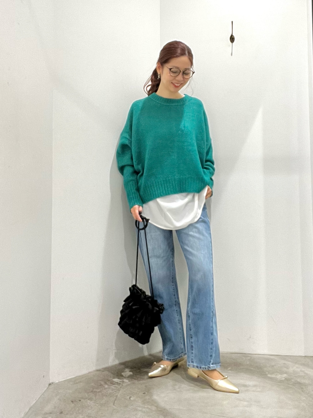 グリーン系のニット/セーター、ホワイト系のシャツ/ブラウス、ブルー系のデニムパンツを着用したレディースの冬コーディネートの1枚目の写真
