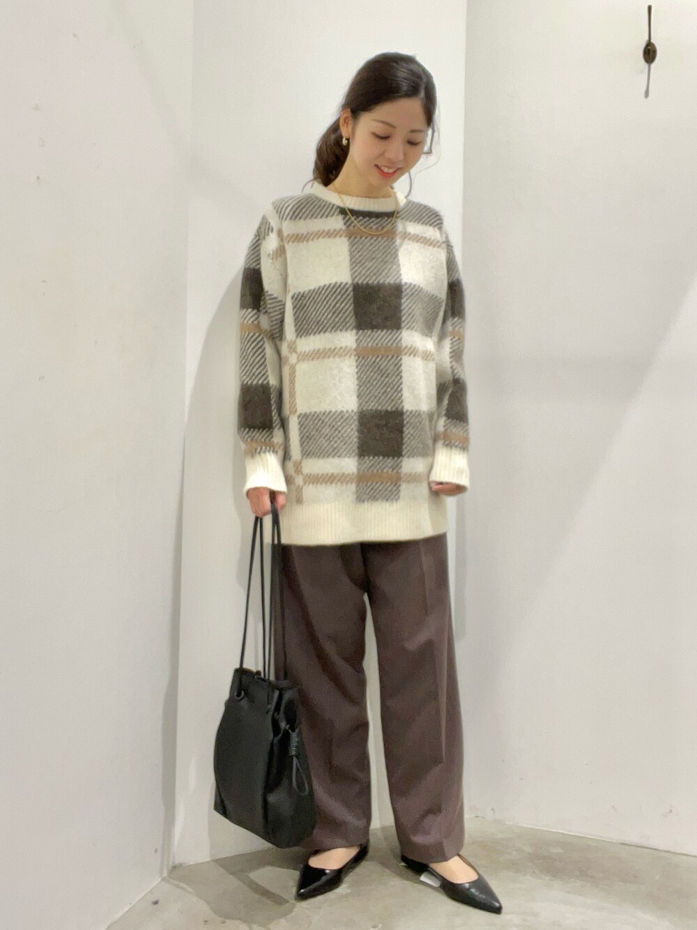 ホワイト系のニット/セーター、ブラウン系のその他パンツ、ブラック系のポーチを着用したレディースの冬コーディネートの1枚目の写真