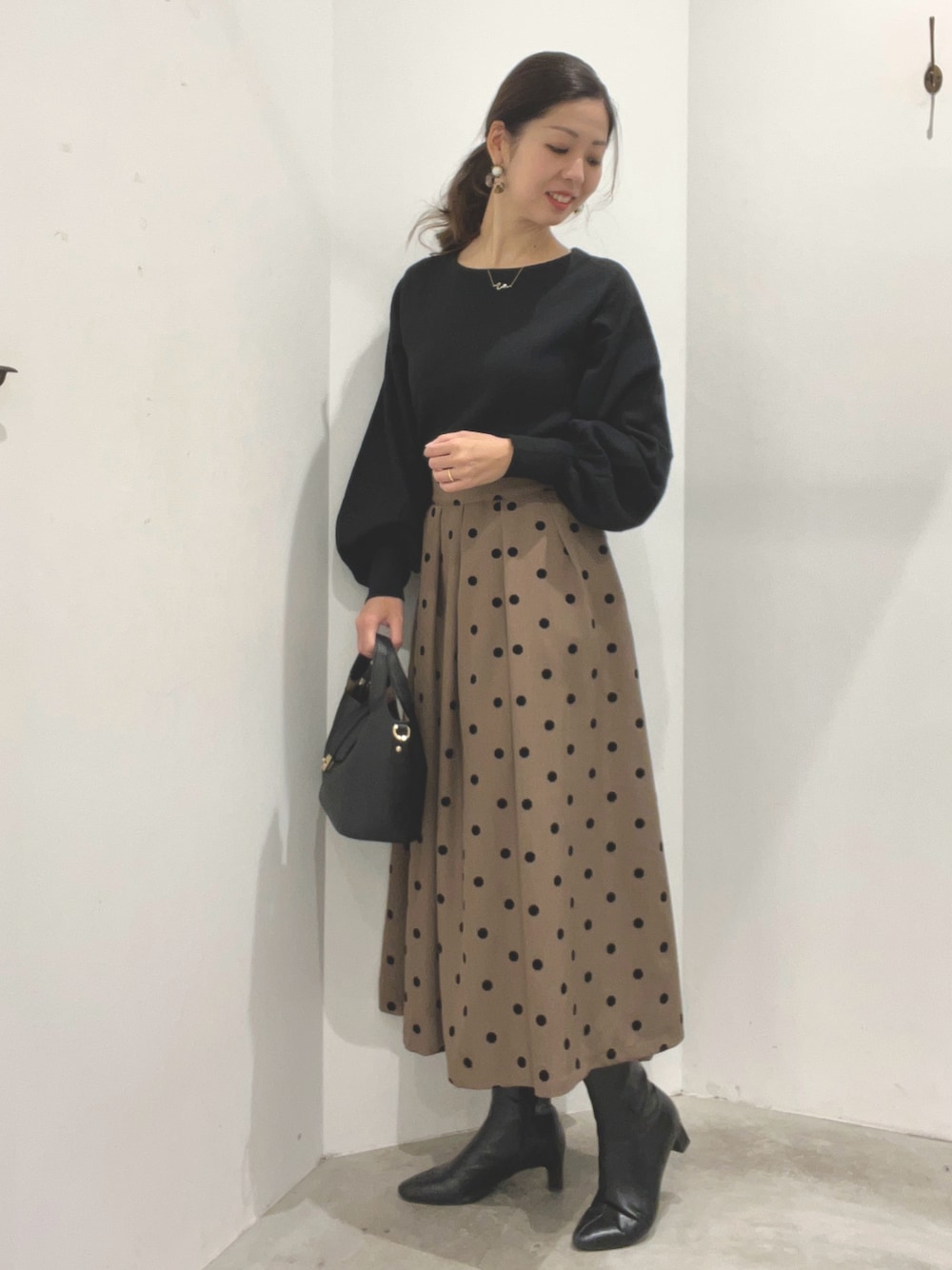 ブラック系のニット/セーター、ベージュ系のスカート、ベージュ系のシューズを着用したレディースの冬コーディネートの1枚目の写真