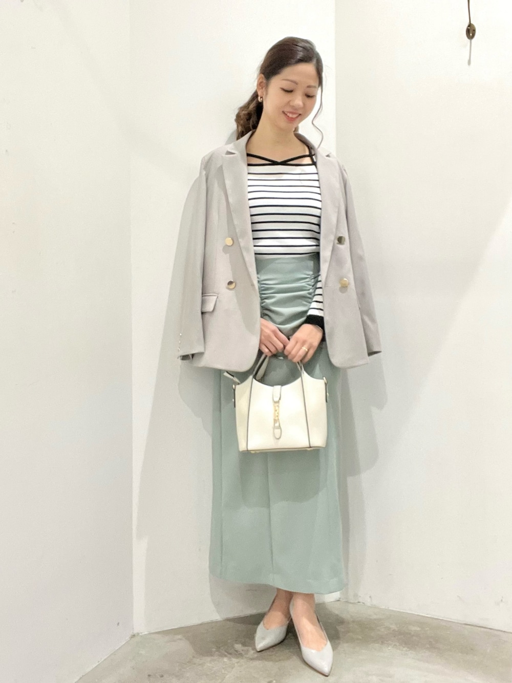 ベージュ系のテーラードジャケット、その他のニット/セーター、グリーン系のスカートを着用したレディースの春コーディネートの1枚目の写真