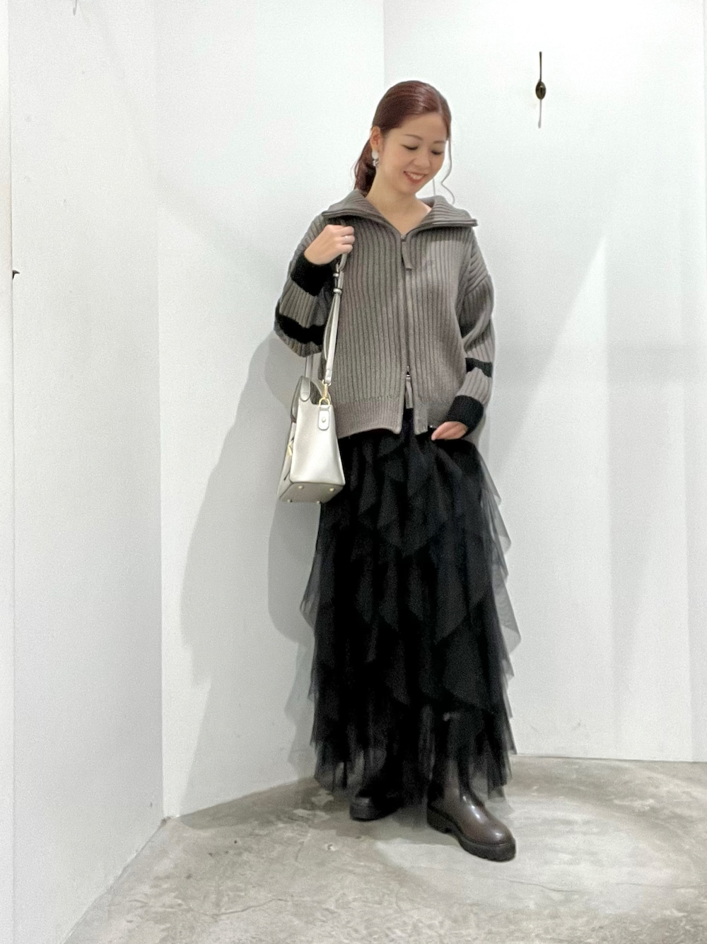 ベージュ系のニット/セーター、ブラック系のスカート、ブラウン系のブーツを着用したレディースの冬コーディネートの1枚目の写真