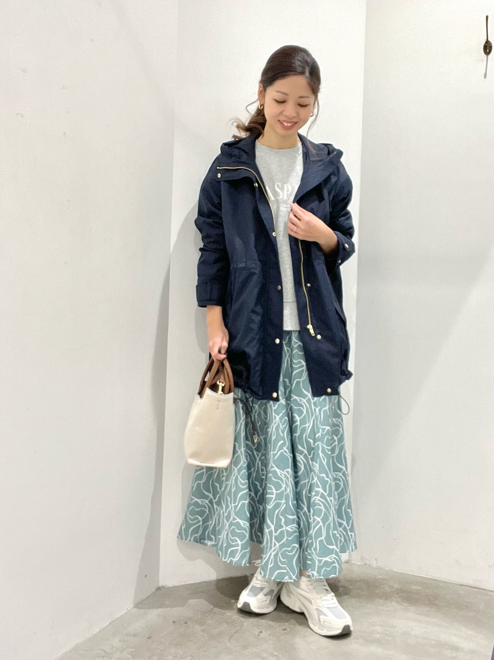 ブルー系のマウンテンパーカー、グレー系のスウェット、グリーン系のスカートを着用したレディースの春コーディネートの1枚目の写真