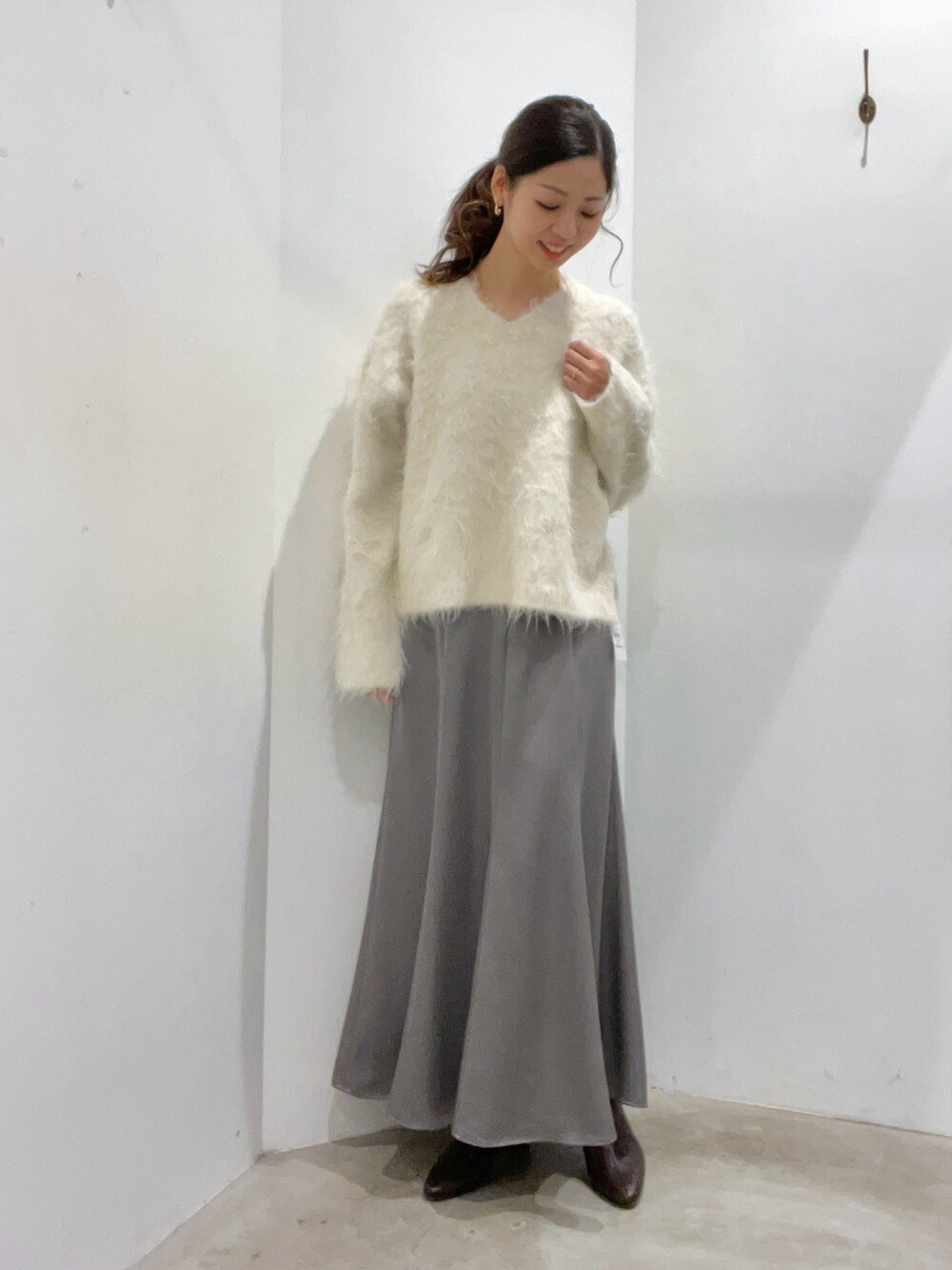 ホワイト系のニット/セーター、グレー系のスカートを着用したレディースの冬コーディネートの1枚目の写真