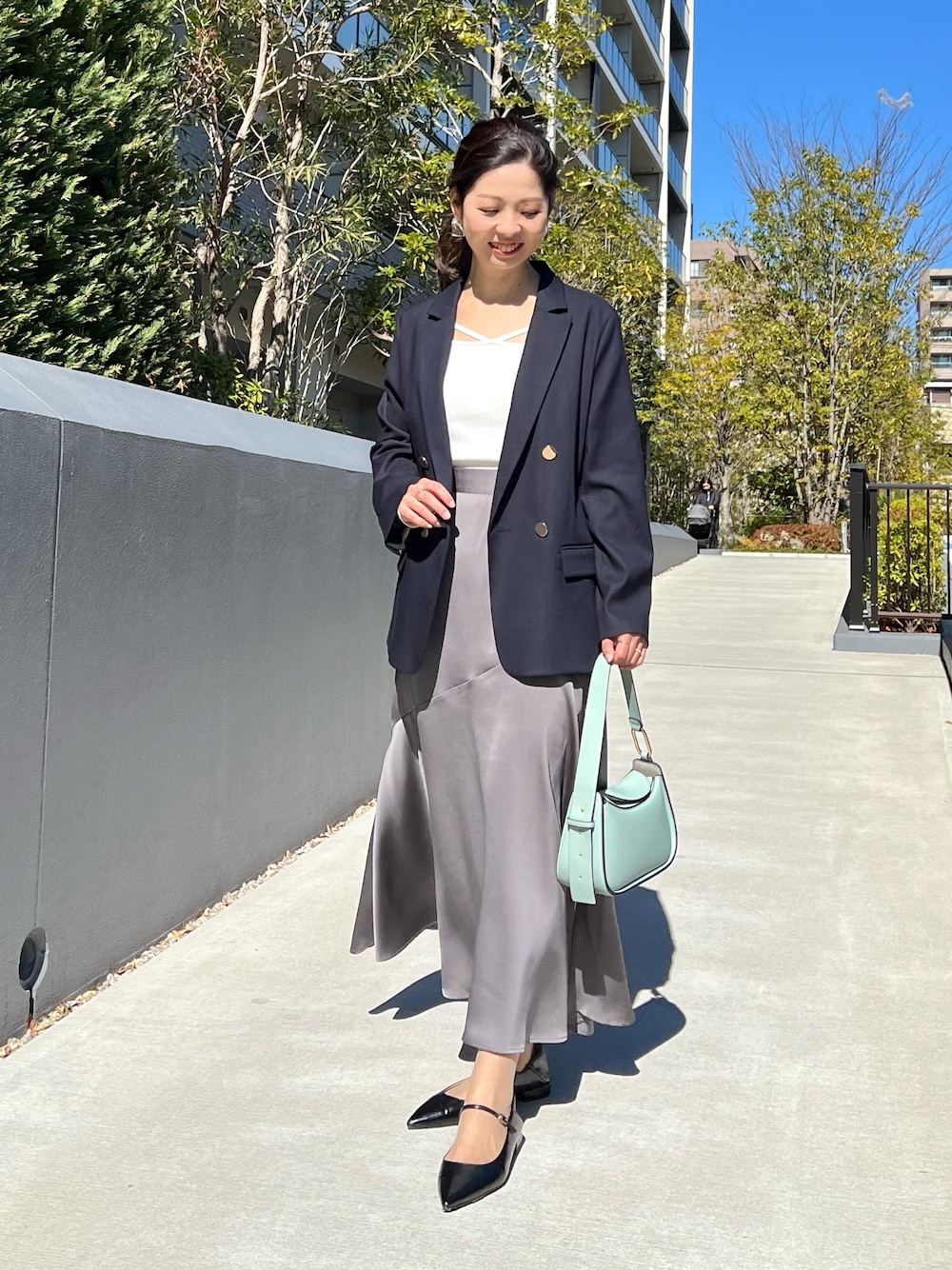 ブルー系のテーラードジャケット、ホワイト系のニット/セーター、グレー系のスカートを着用したレディースの春コーディネートの1枚目の写真