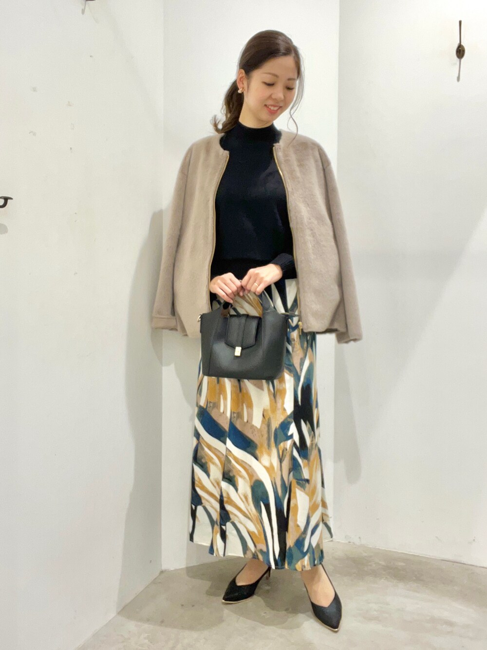 ブラウン系のその他アウター、ベージュ系のスカート、ブラック系のハンドバッグを着用したレディースの秋コーディネートの1枚目の写真