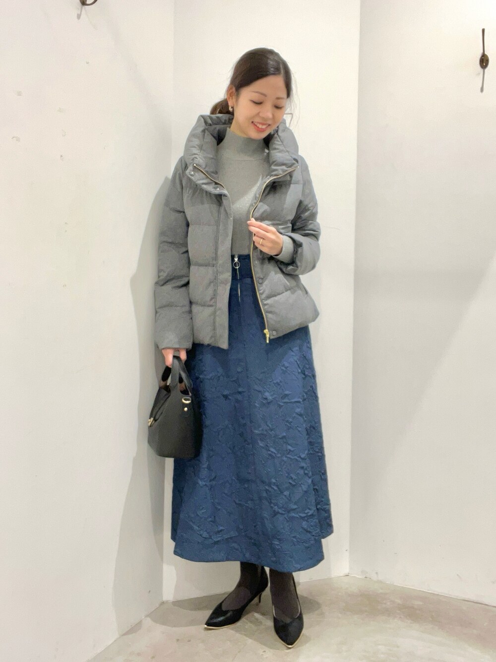 グレー系のブルゾン、グレー系のニット/セーター、ブルー系のスカートを着用したレディースの冬コーディネートの1枚目の写真