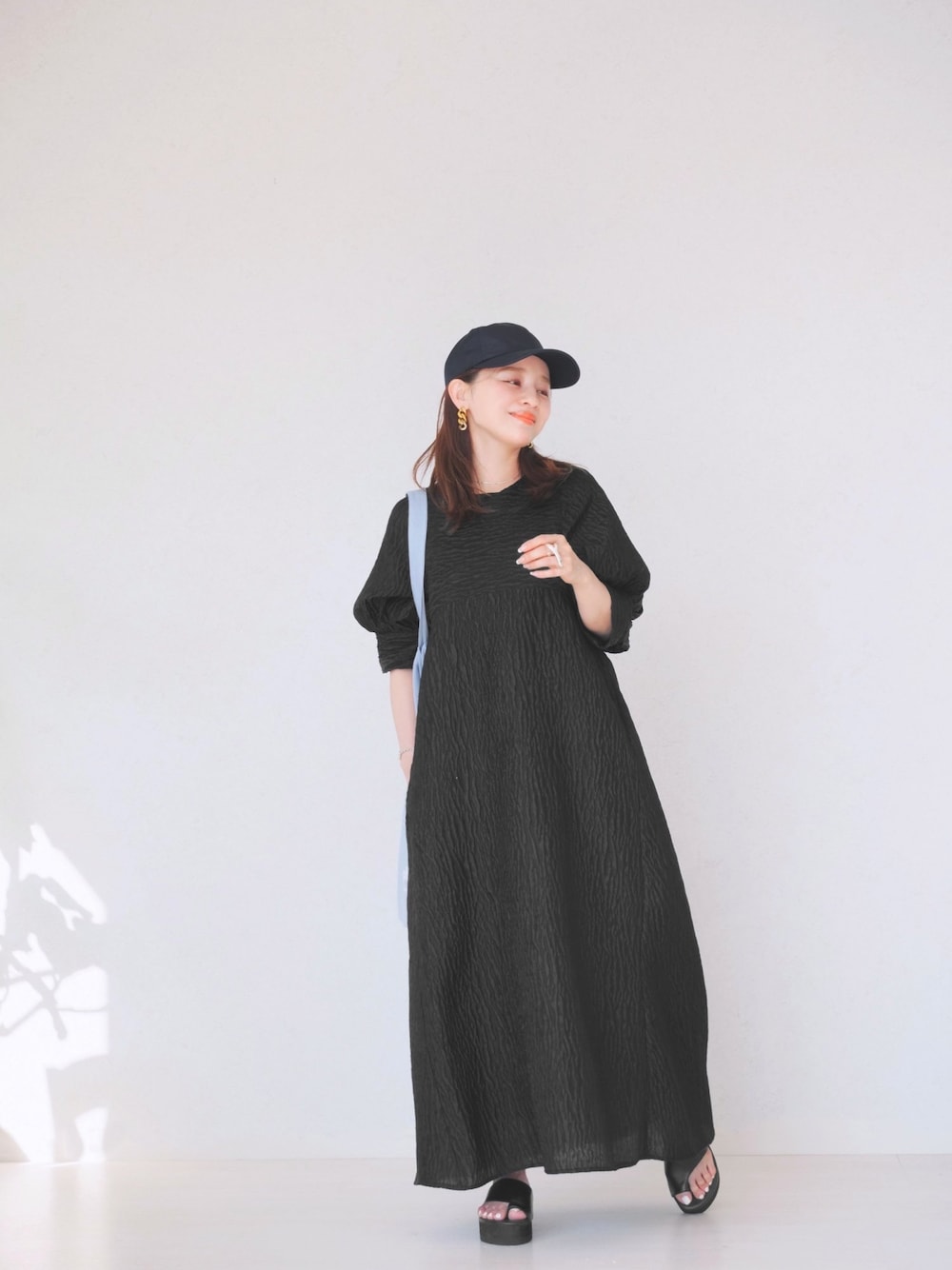 ブラック系のワンピース、ブルー系のトートバッグ、ブラック系のシューズを着用したレディースの春コーディネートの1枚目の写真