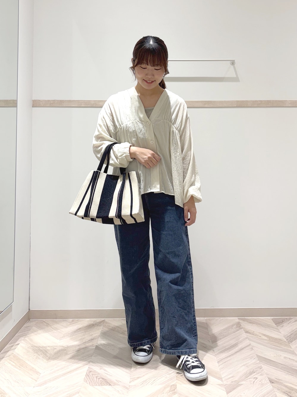 ホワイト系のカーディガン/ボレロ、ゴールド系のタンクトップ、ブルー系のデニムパンツを着用したレディースの秋コーディネートの1枚目の写真
