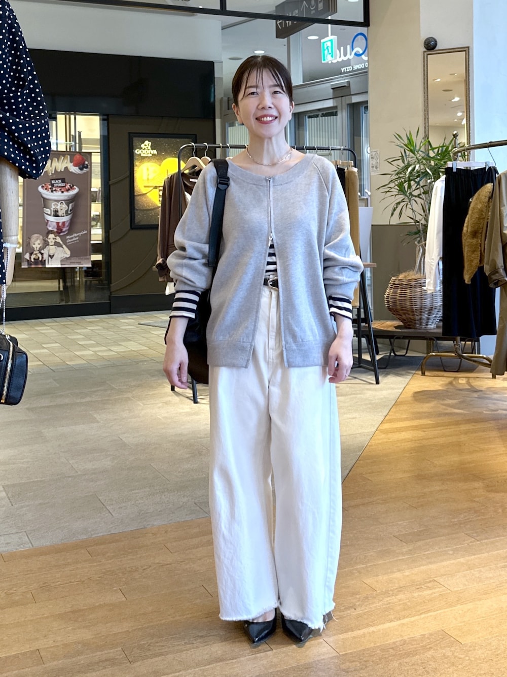 ブラック系のパンプス、ホワイト系のデニムパンツ、グレー系のニット/セーターを着用したレディースの秋コーディネートの1枚目の写真