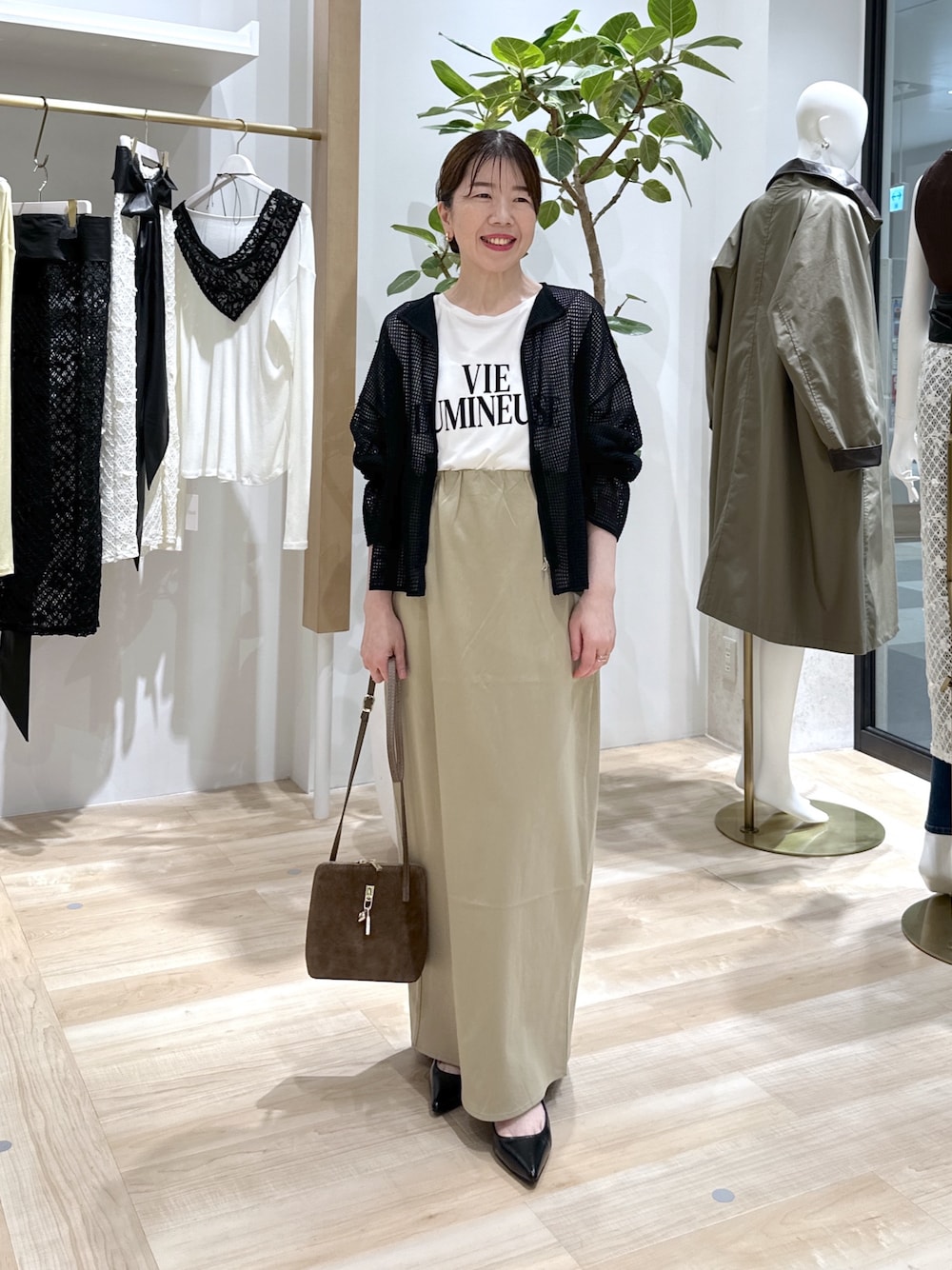 ベージュ系のスカート、ブラック系のパンプス、ブラウン系のショルダーバッグを着用したレディースの夏コーディネートの1枚目の写真