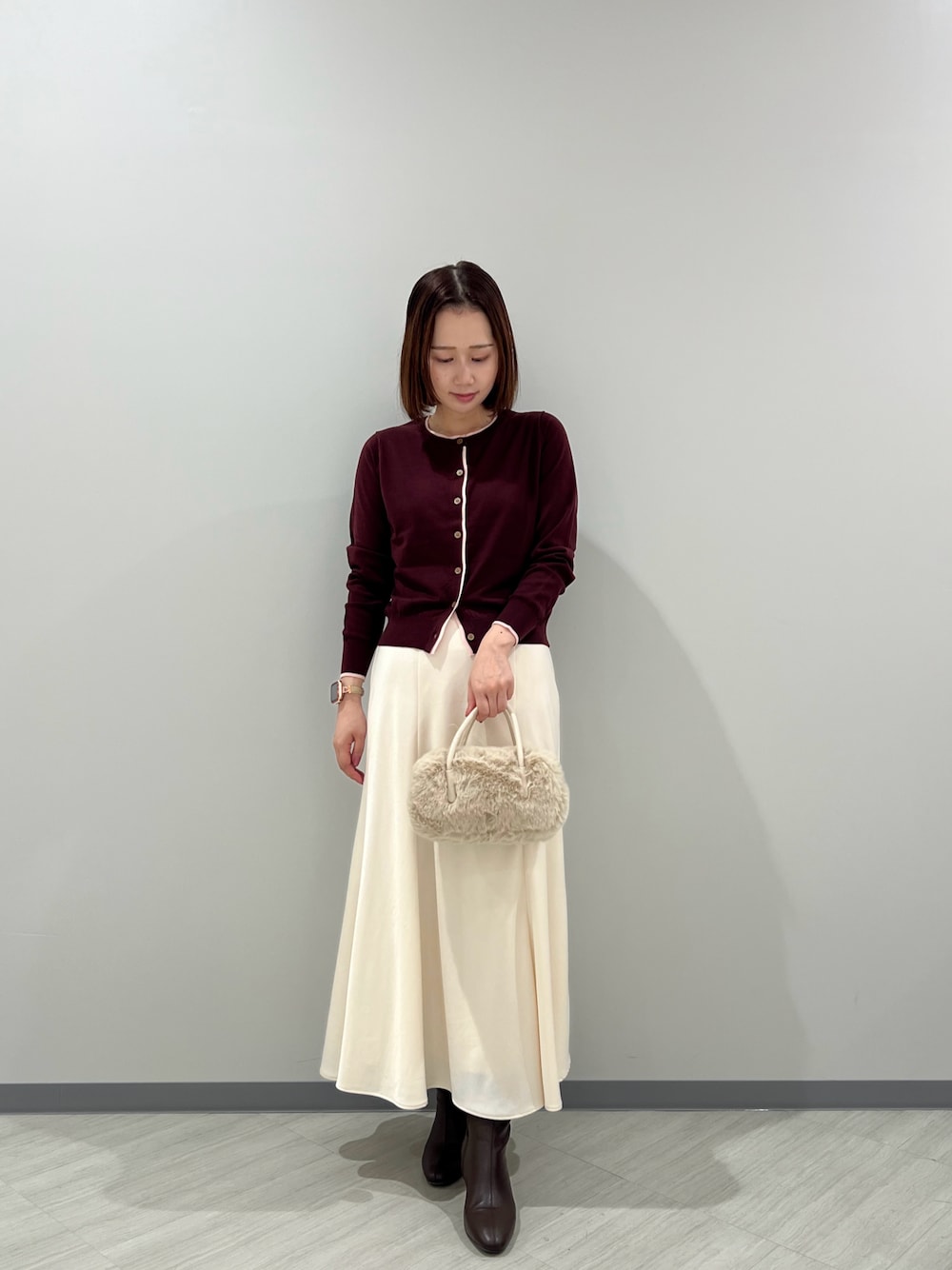レッド系のカーディガン/ボレロ、ホワイト系のスカート、ホワイト系のボストンバッグを着用したレディースの秋コーディネートの1枚目の写真