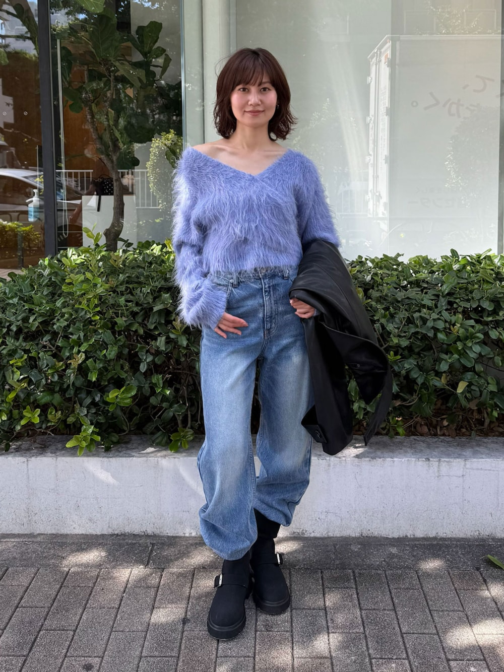 ブルー系のニット/セーター、ブラック系のブルゾン、ブルー系のデニムパンツを着用したレディースの秋コーディネートの1枚目の写真