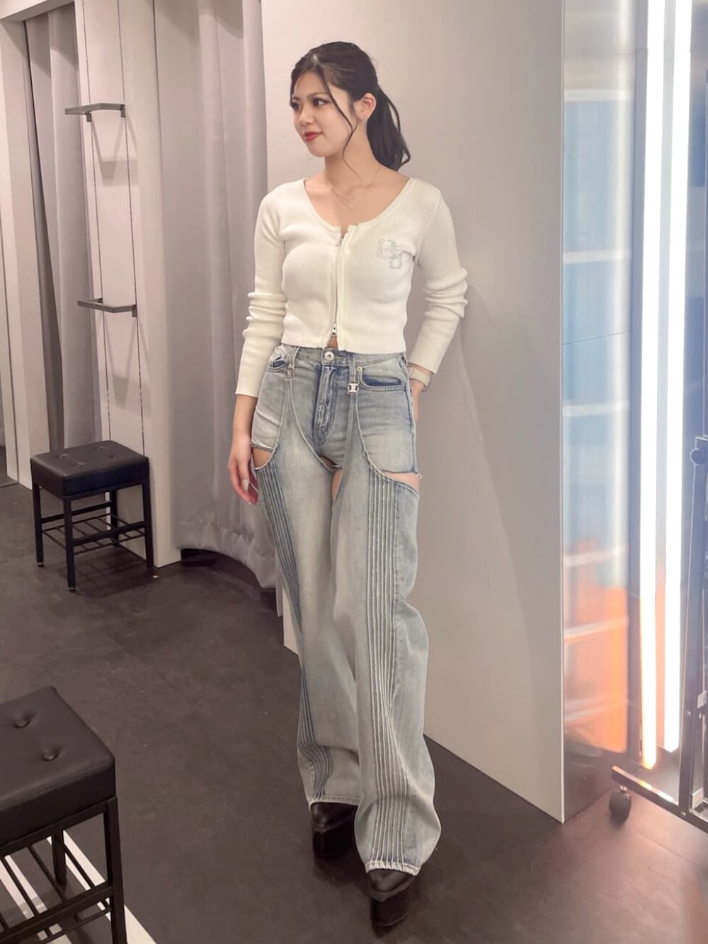 ブラック系のブーツ、ホワイト系のニット/セーター、ブルー系のデニムパンツを着用したレディースの春コーディネートの1枚目の写真