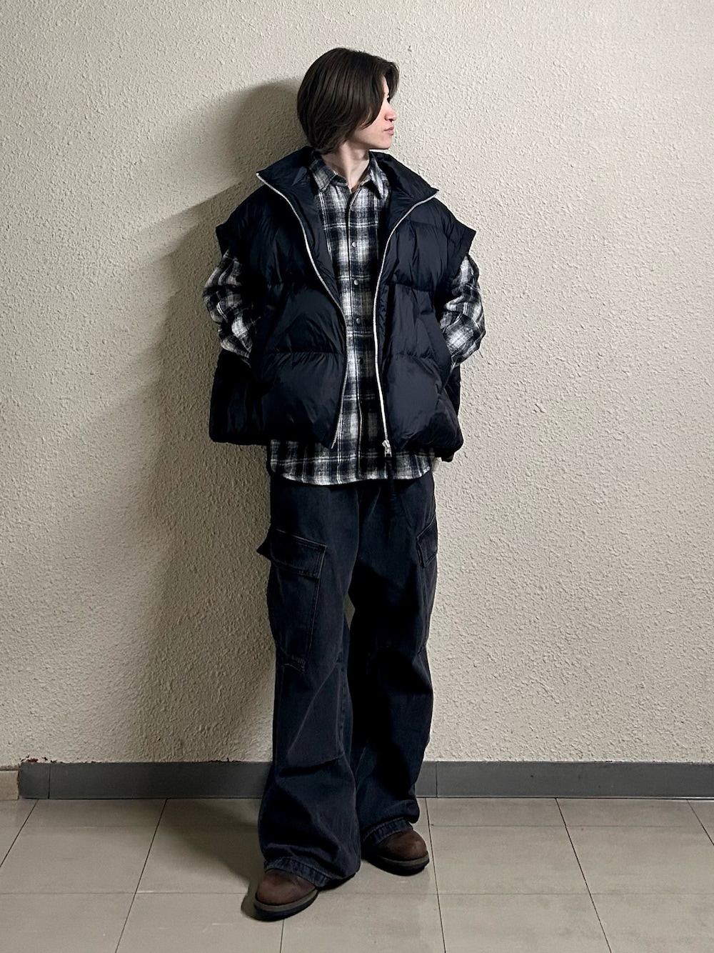 ブラック系のカーゴパンツ、ブラック系のダウンベスト、ブラウン系のブーツを着用したメンズの春コーディネートの1枚目の写真