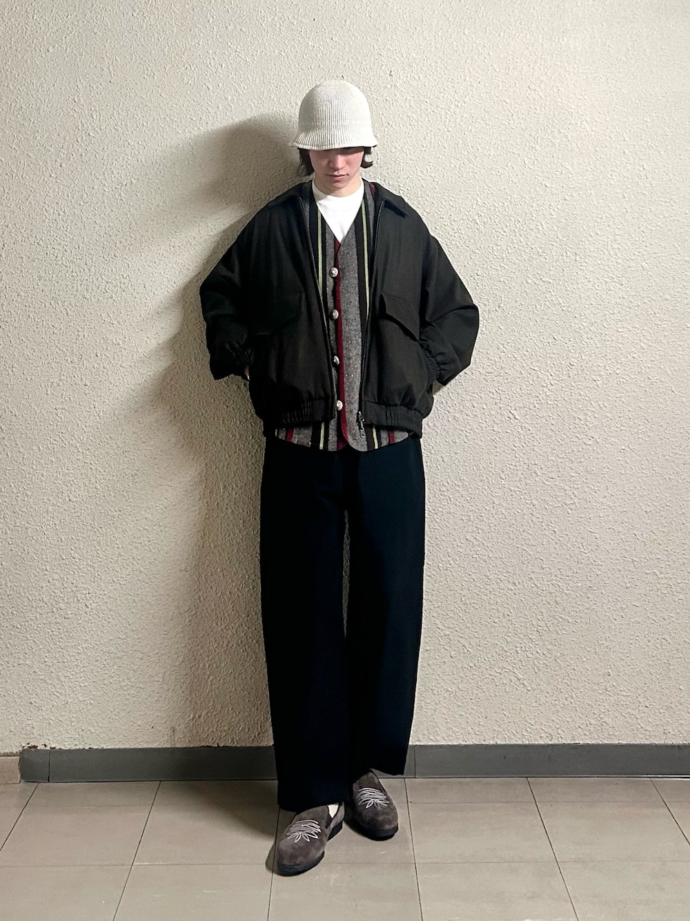 レッド系のベスト、ブラック系のパンツ、ブラウン系のシューズを着用したメンズの春コーディネートの1枚目の写真