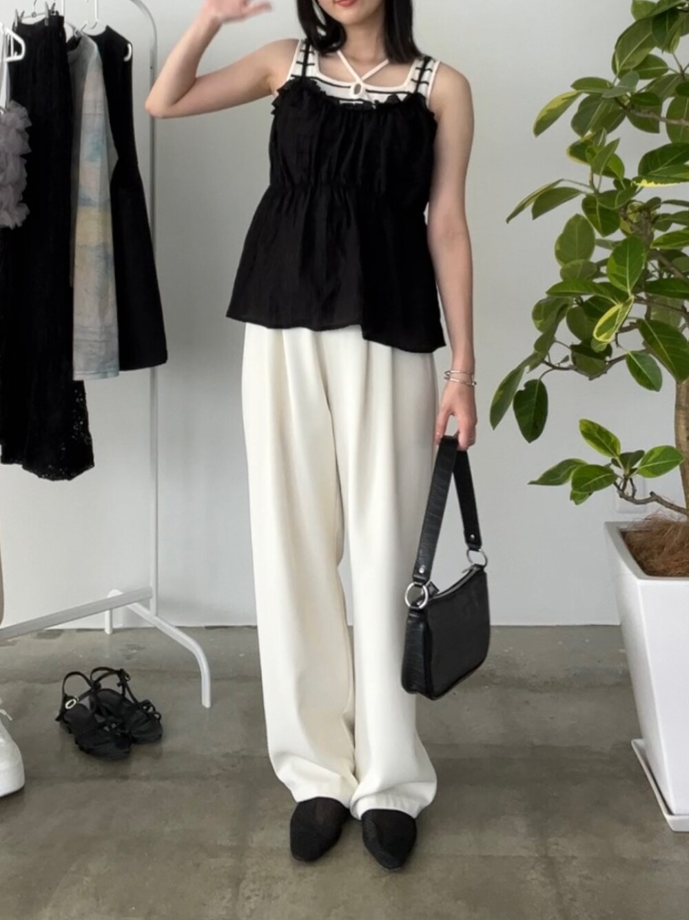 ホワイト系のスラックス、ホワイト系のタンクトップ、ブラック系のトップスを着用したレディースの夏コーディネートの1枚目の写真