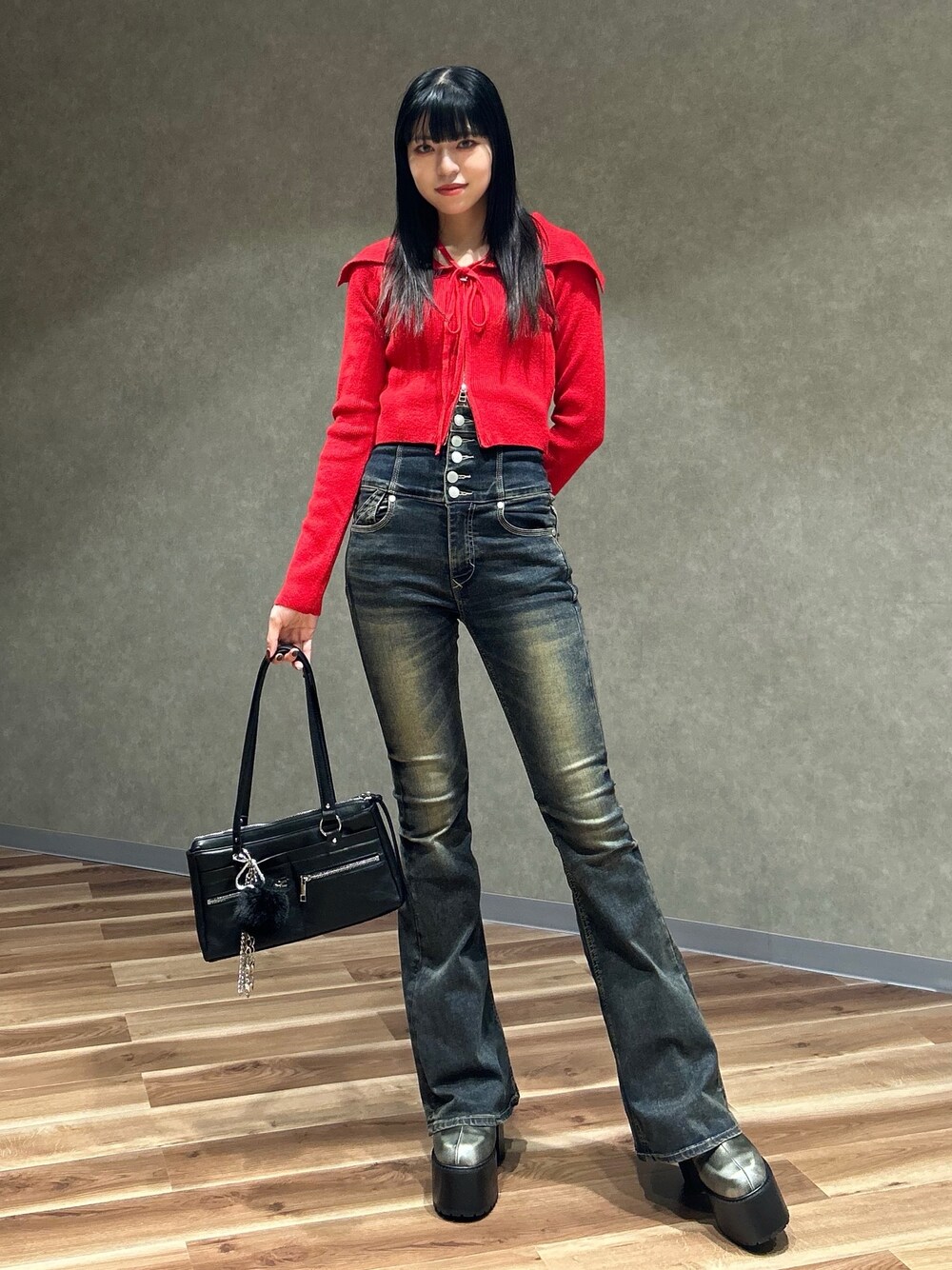 レッド系のニット/セーター、ブルー系のデニムパンツ、ブラック系のショルダーバッグを着用したレディースの秋コーディネートの1枚目の写真