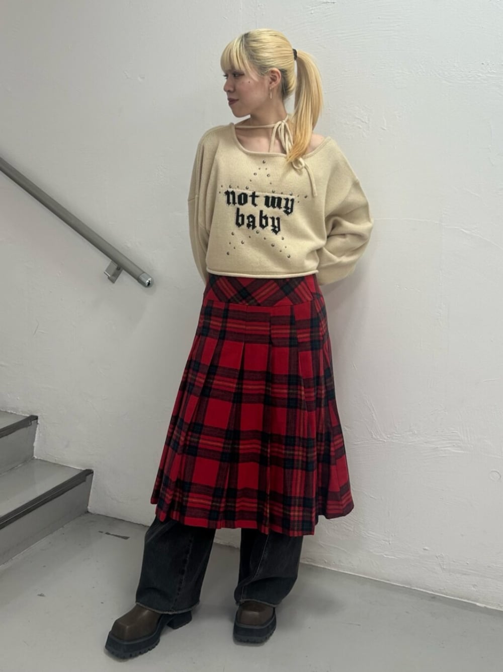 ブラック系のデニムパンツ、ブラウン系のブーツ、ホワイト系のニット/セーターを着用したレディースの冬コーディネートの1枚目の写真