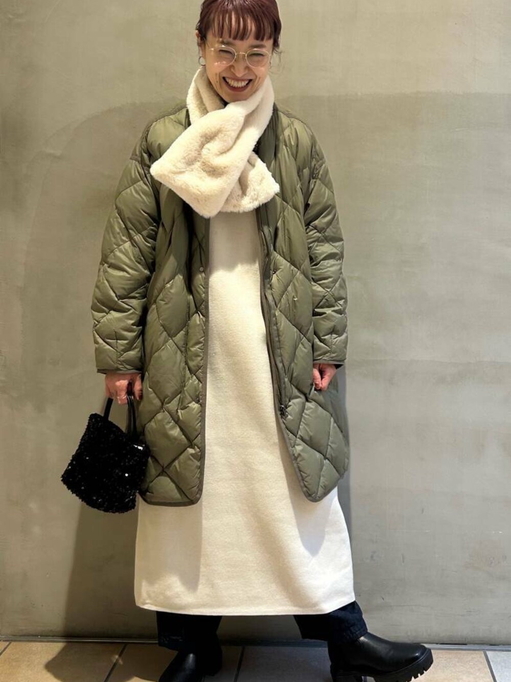 ブラック系のショルダーバッグ、グリーン系のダウンジャケット/コート、ブラック系のブーツを着用したレディースの冬コーディネートの1枚目の写真