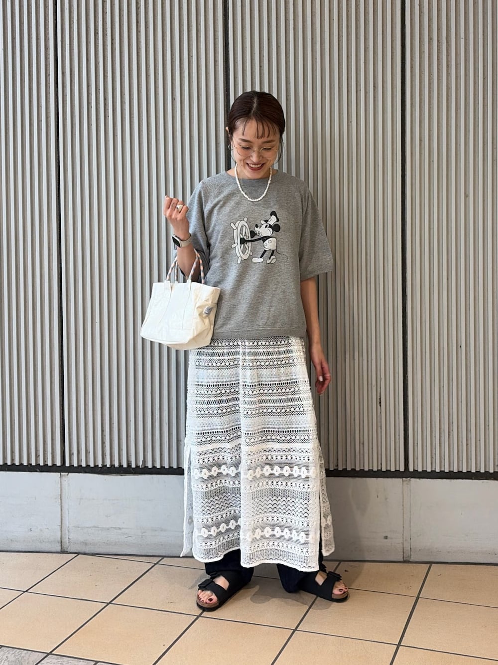グレー系のシャツ/ブラウス、ホワイト系のショルダーバッグ、ブラック系のサンダルを着用したレディースの夏コーディネートの1枚目の写真
