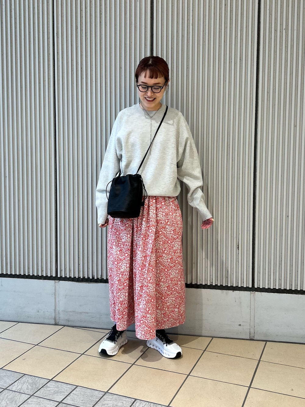 レッド系のスカート、グレー系のニット/セーター、ブラック系のスニーカーを着用したレディースの春コーディネートの1枚目の写真