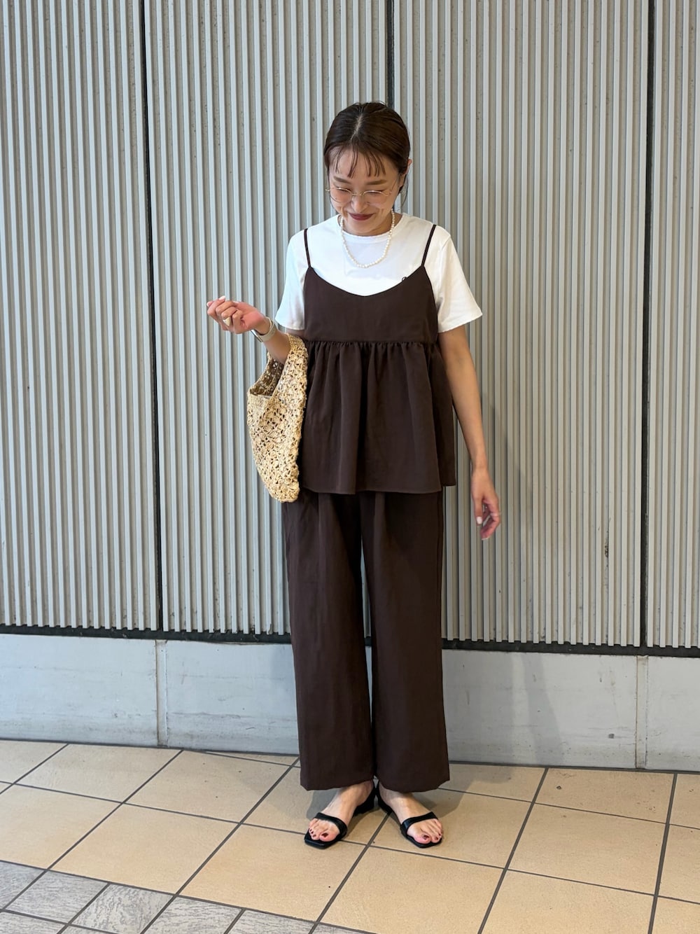 ホワイト系のTシャツ/カットソー、ブラック系のサンダル、ベージュ系のハンドバッグを着用したレディースの夏コーディネートの1枚目の写真