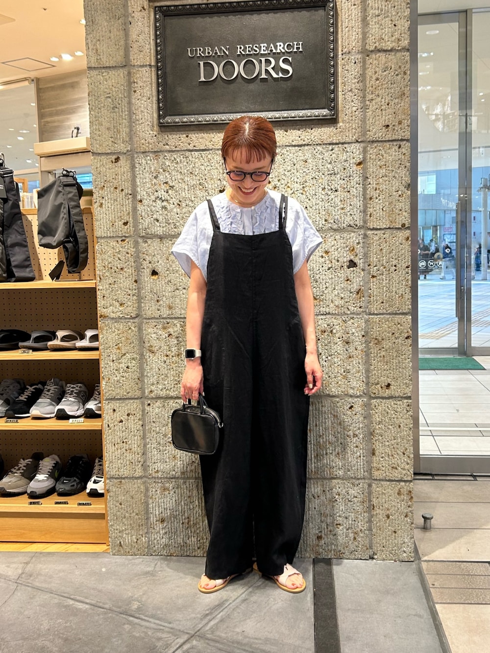 ブラック系のサロペット/オーバーオール、ブルー系のシャツ/ブラウス、ブラック系のショルダーバッグを着用したレディースの春コーディネートの1枚目の写真