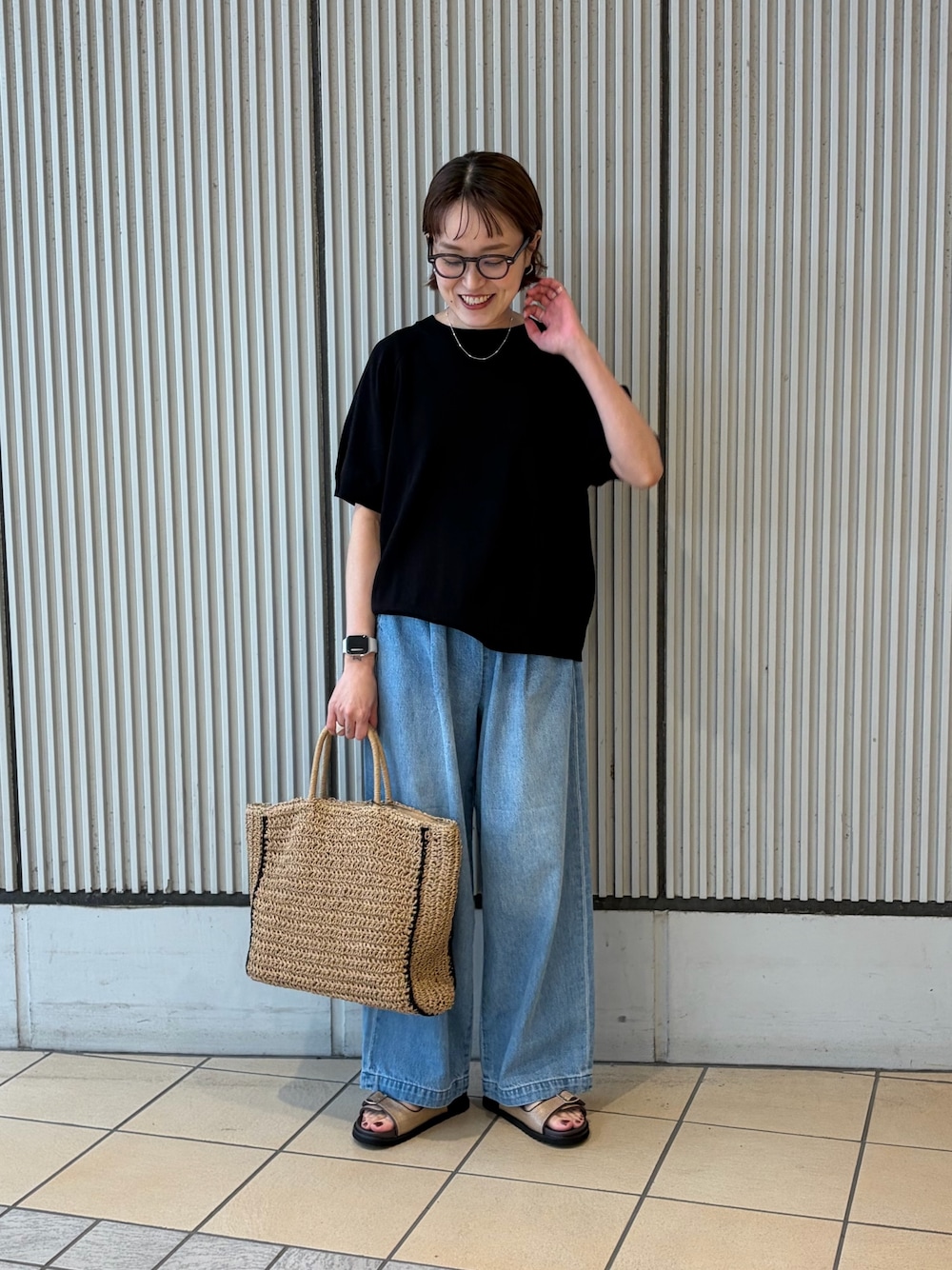 ブラック系のニット/セーター、ブルー系のデニムパンツ、ベージュ系のサンダルを着用したレディースの夏コーディネートの1枚目の写真