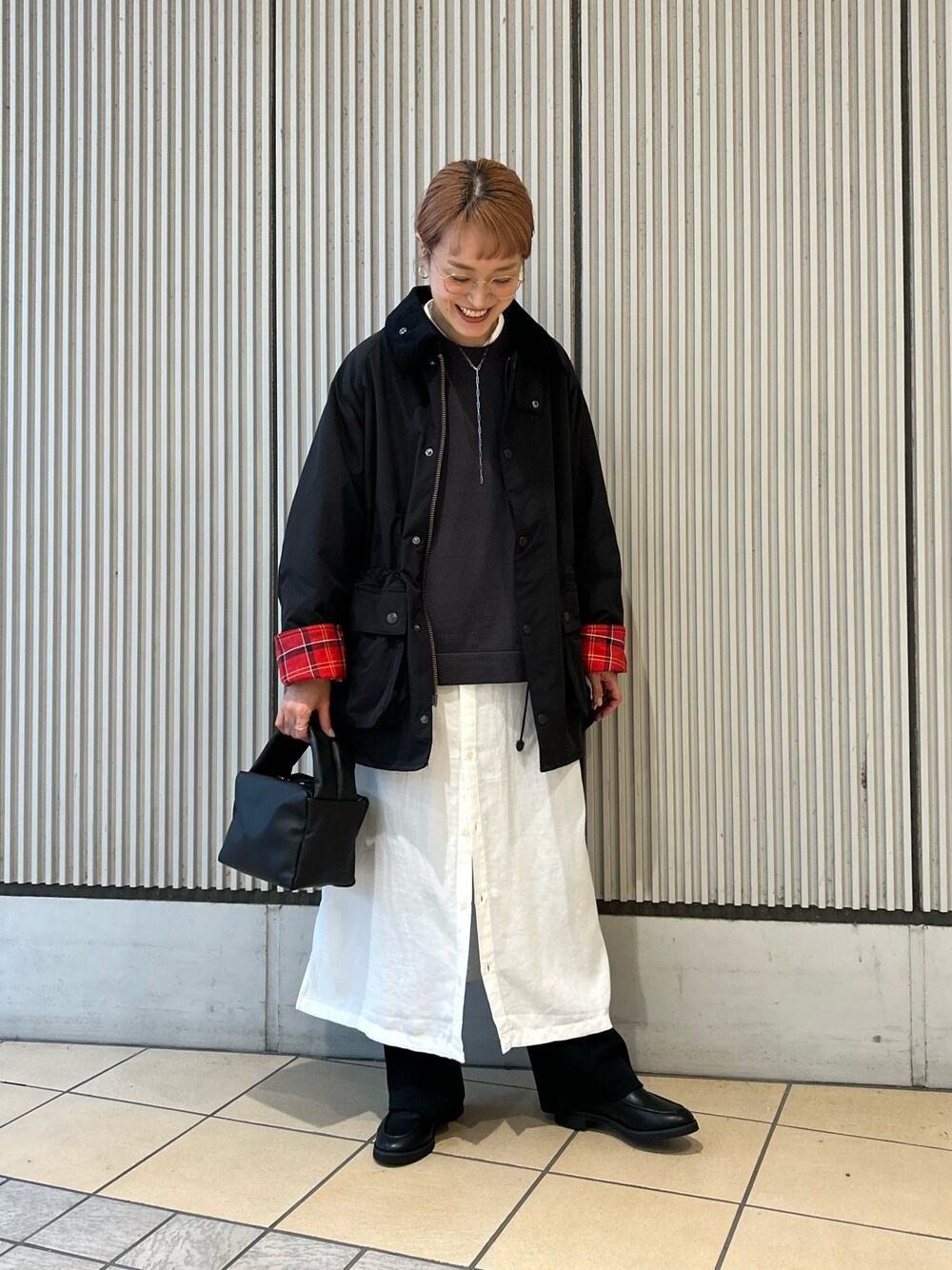 グレー系のベスト、ホワイト系のワンピース、ブラック系のその他パンツを着用したレディースの秋コーディネートの1枚目の写真