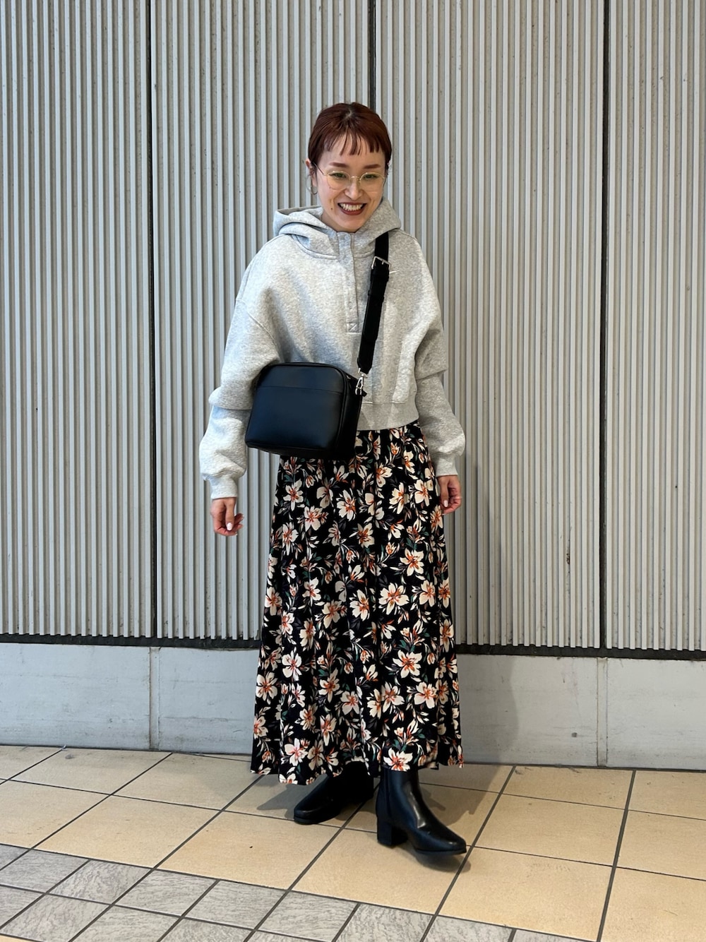 グレー系のパーカー、ブラック系のスカート、ブラック系のショルダーバッグを着用したレディースの冬コーディネートの1枚目の写真