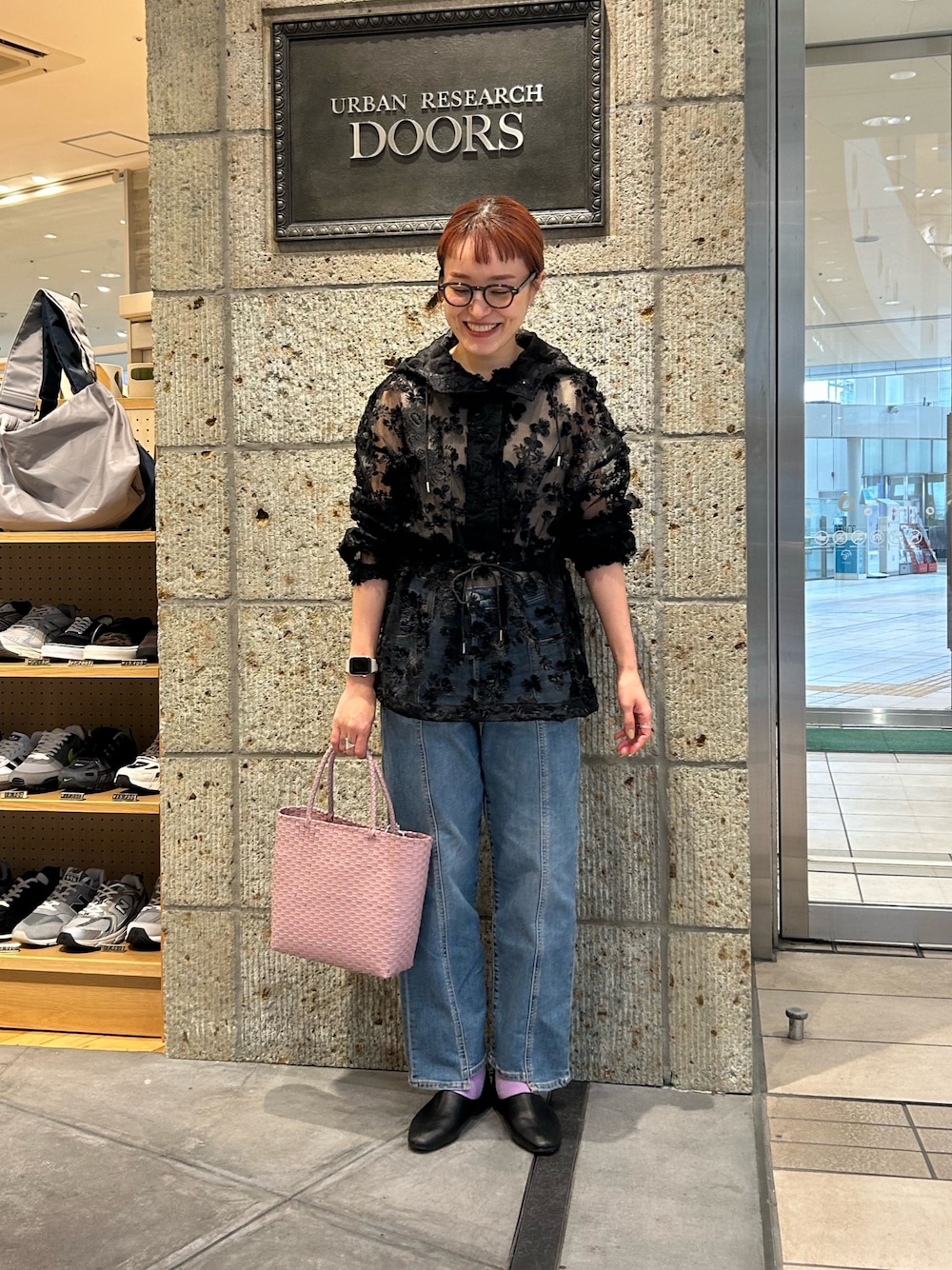 ブラック系のパーカー、ブルー系のデニムパンツ、ピンク系のハンドバッグを着用したレディースの春コーディネートの1枚目の写真