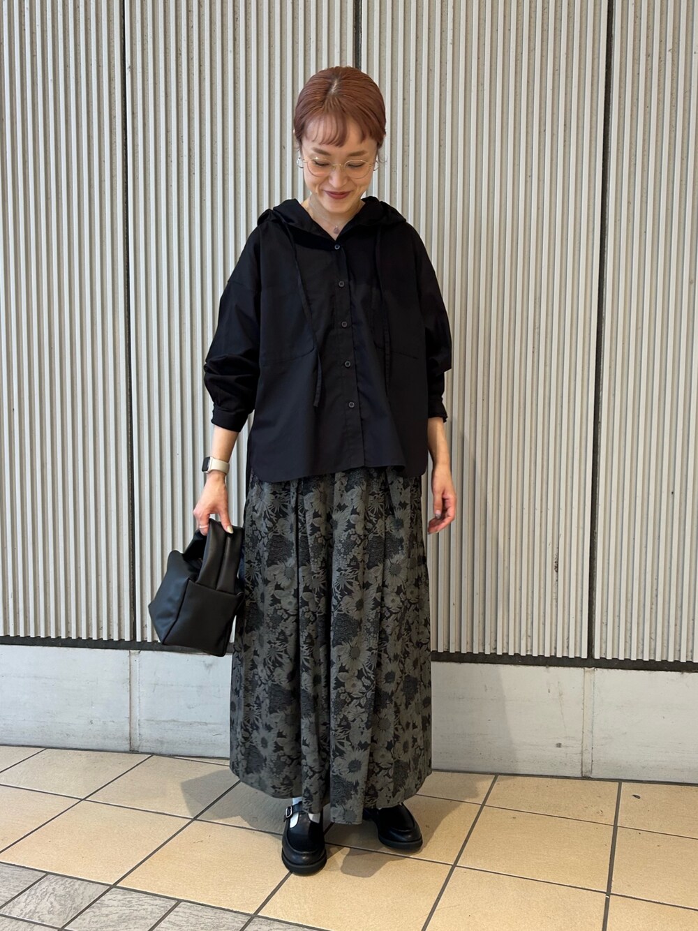 ブラック系のシャツ/ブラウス、グレー系のスカート、ブラック系のハンドバッグを着用したレディースの秋コーディネートの1枚目の写真