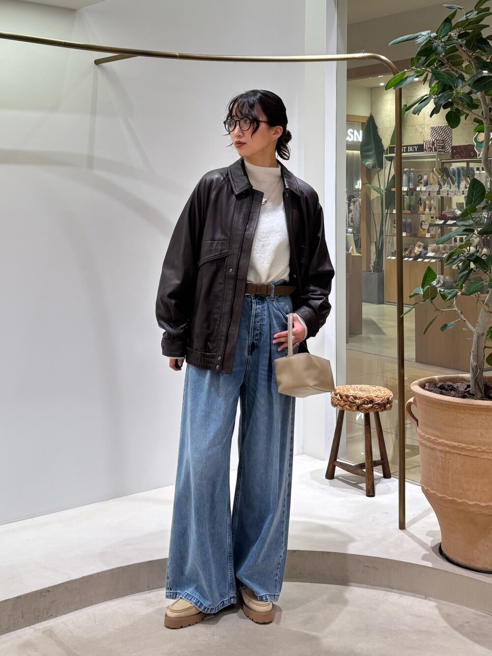 ブラウン系のブルゾン、ホワイト系のニット/セーター、ブルー系のデニムパンツを着用したレディースの秋コーディネートの1枚目の写真