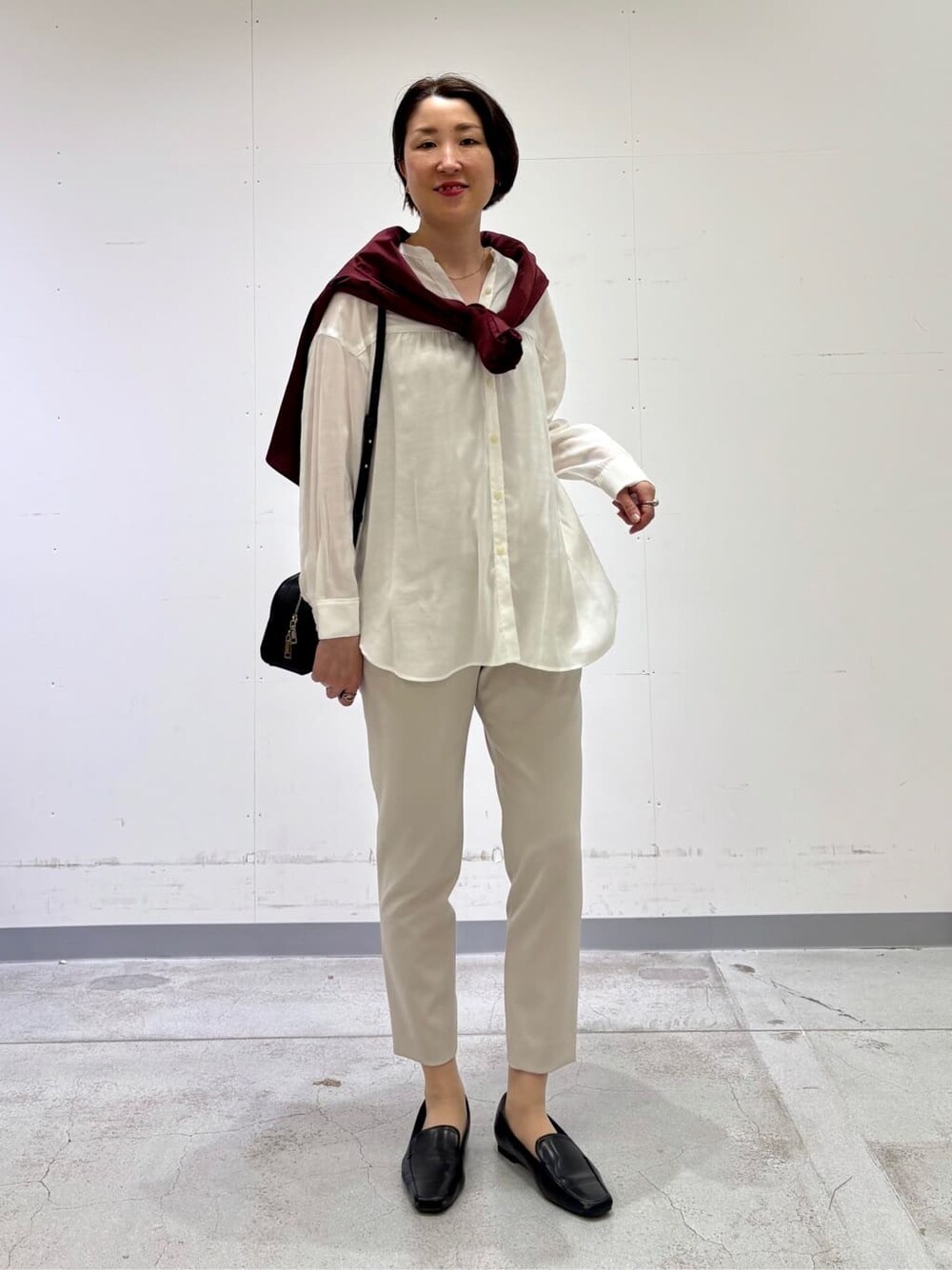 ホワイト系のシャツ/ブラウス、レッド系のニット/セーター、ベージュ系のその他パンツを着用したレディースの春コーディネートの1枚目の写真