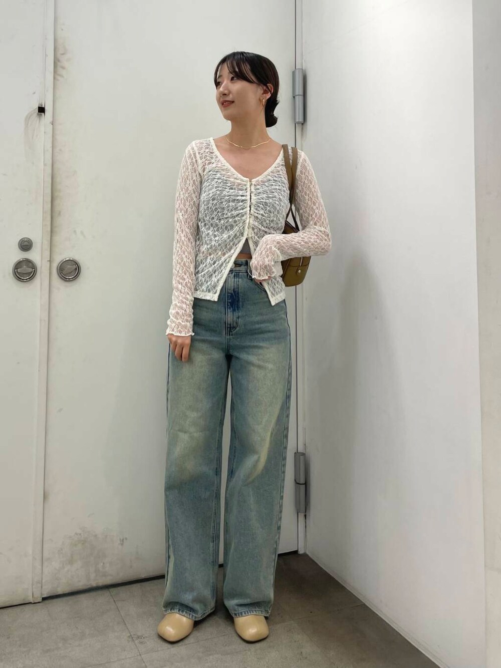 ベージュ系のサンダル、グリーン系のボストンバッグ、ブルー系のデニムパンツを着用したレディースの秋コーディネートの1枚目の写真