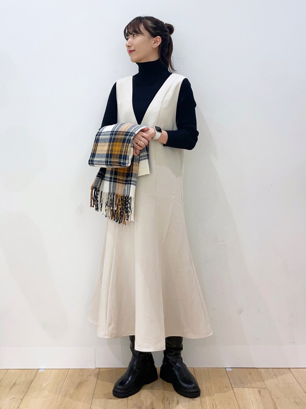 ブラック系のニット/セーター、ホワイト系のジャンパースカート、ブラック系のブーツを着用したレディースの秋コーディネートの1枚目の写真