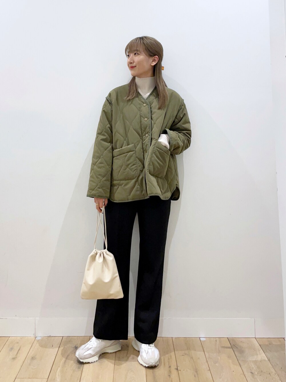 グリーン系のナイロンジャケット、ベージュ系のショルダーバッグ、ブラック系のその他パンツを着用したレディースの冬コーディネートの1枚目の写真