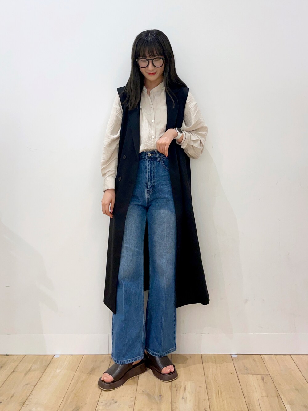 ベージュ系のシャツ/ブラウス、ブラック系のベスト、ブルー系のデニムパンツを着用したレディースの春コーディネートの1枚目の写真