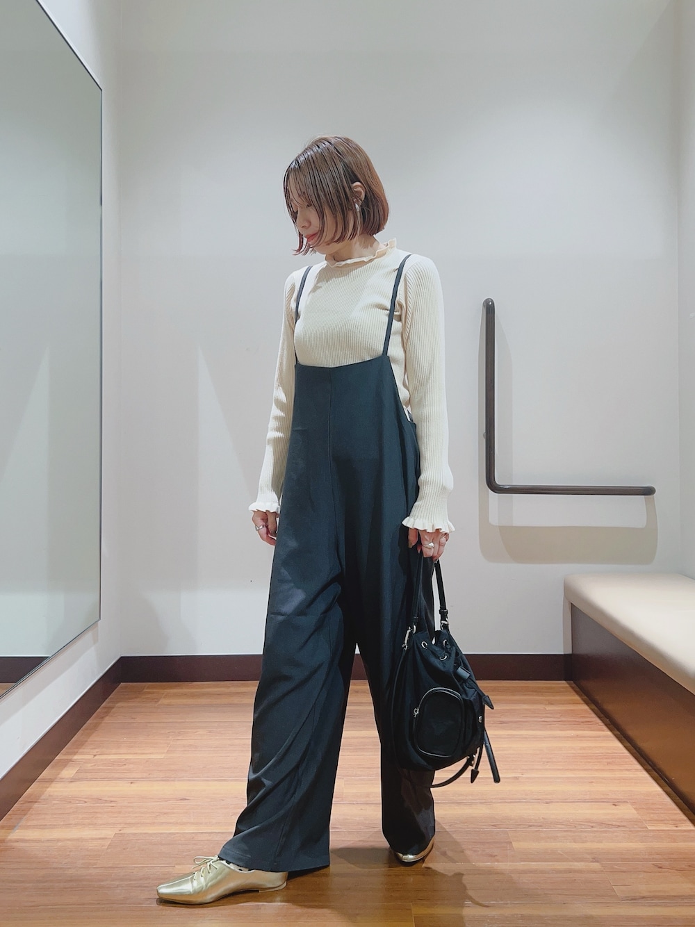 グレー系のサロペット/オーバーオール、ホワイト系のニット/セーター、ブラック系のハンドバッグを着用したレディースの秋コーディネートの1枚目の写真