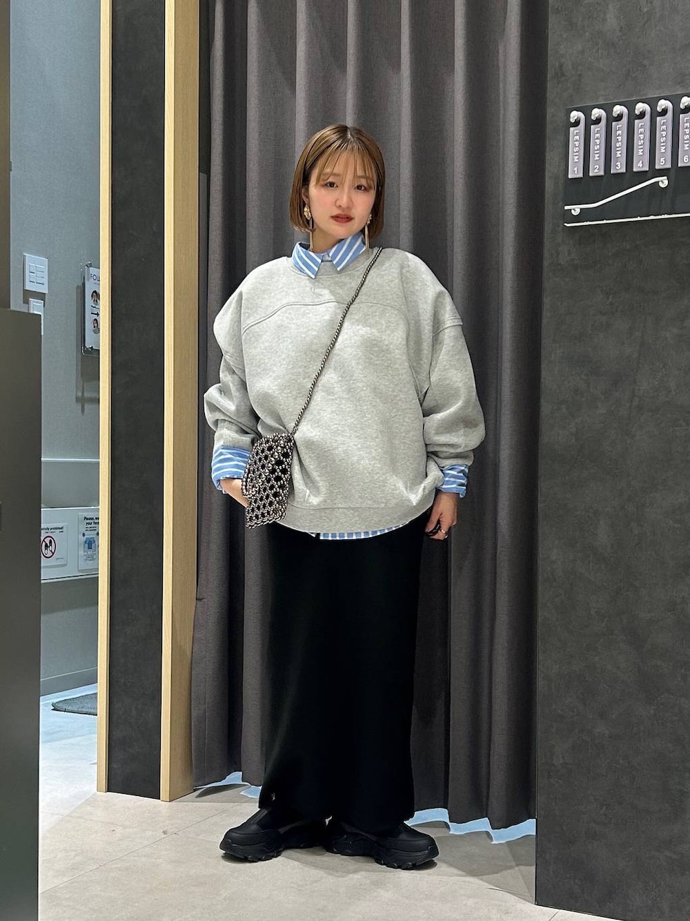 ブラック系のスカート、グレー系のスウェット、ブラック系のスニーカーを着用したレディースの秋コーディネートの1枚目の写真