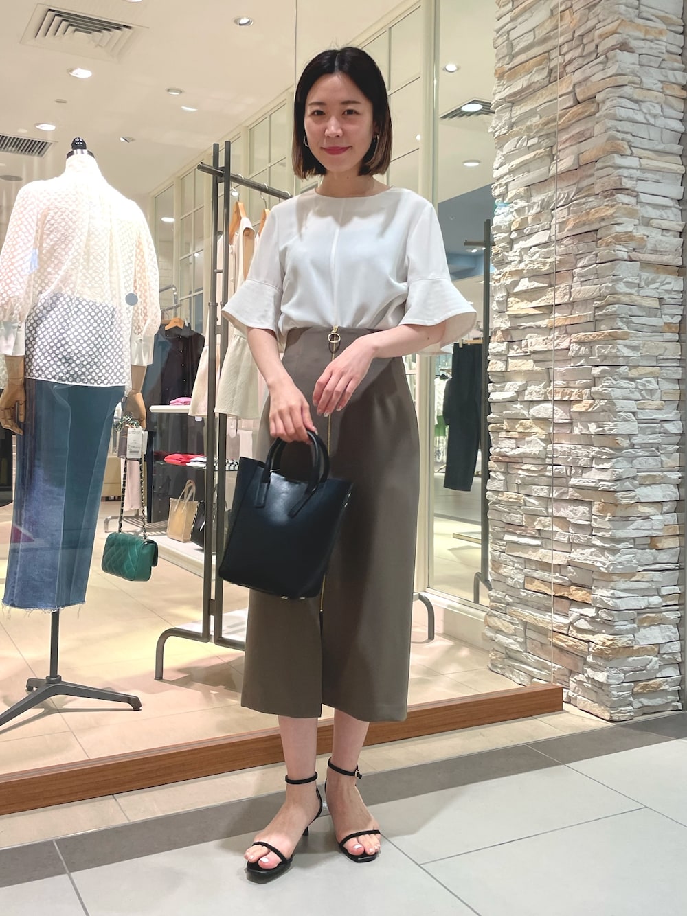 ブラック系のトートバッグ、ブラック系のサンダル、ホワイト系のシャツ/ブラウスを着用したレディースの夏コーディネートの1枚目の写真