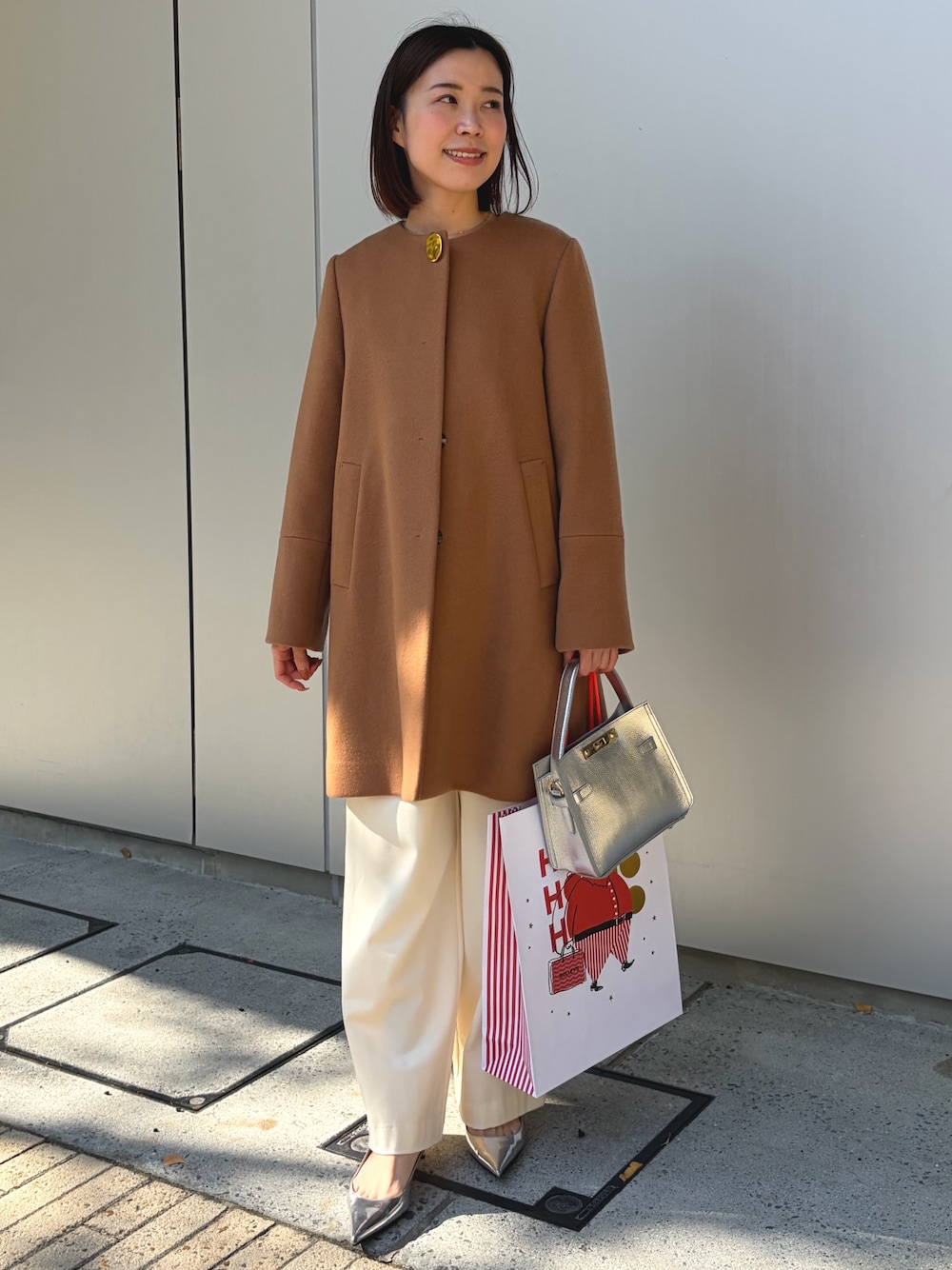 イエロー系のノーカラーコート、シルバー系のショルダーバッグ、ホワイト系のその他パンツを着用したレディースの秋コーディネートの1枚目の写真