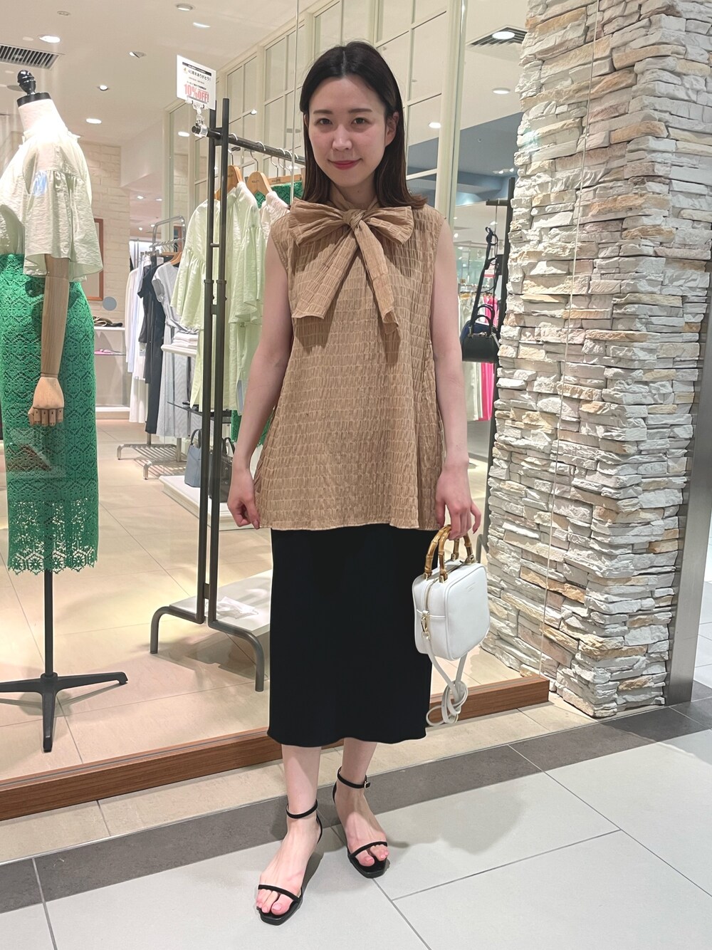 イエロー系のシャツ/ブラウス、ブラック系のスカート、ホワイト系のハンドバッグを着用したレディースの春コーディネートの1枚目の写真