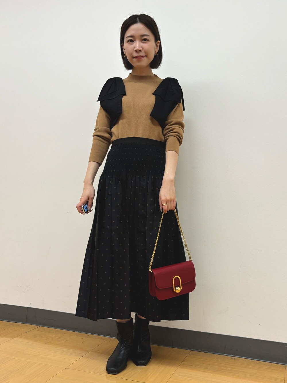 イエロー系のニット/セーター、ブラウン系のスカートを着用したレディースの秋コーディネートの1枚目の写真