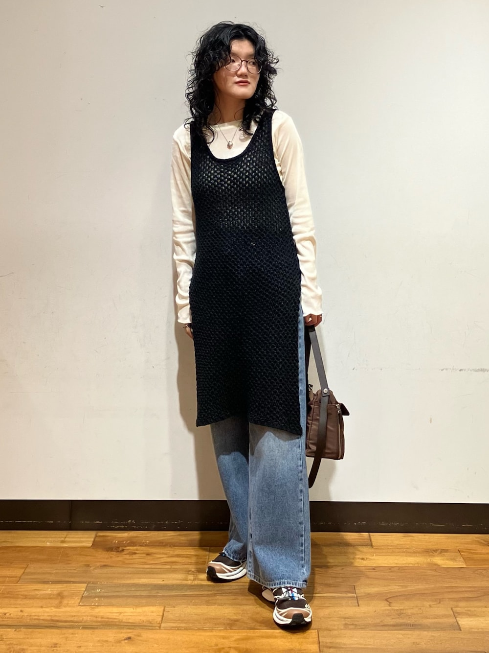ブルー系のデニムパンツ、ブラウン系のスニーカー、ブラウン系のショルダーバッグを着用したレディースの秋コーディネートの1枚目の写真