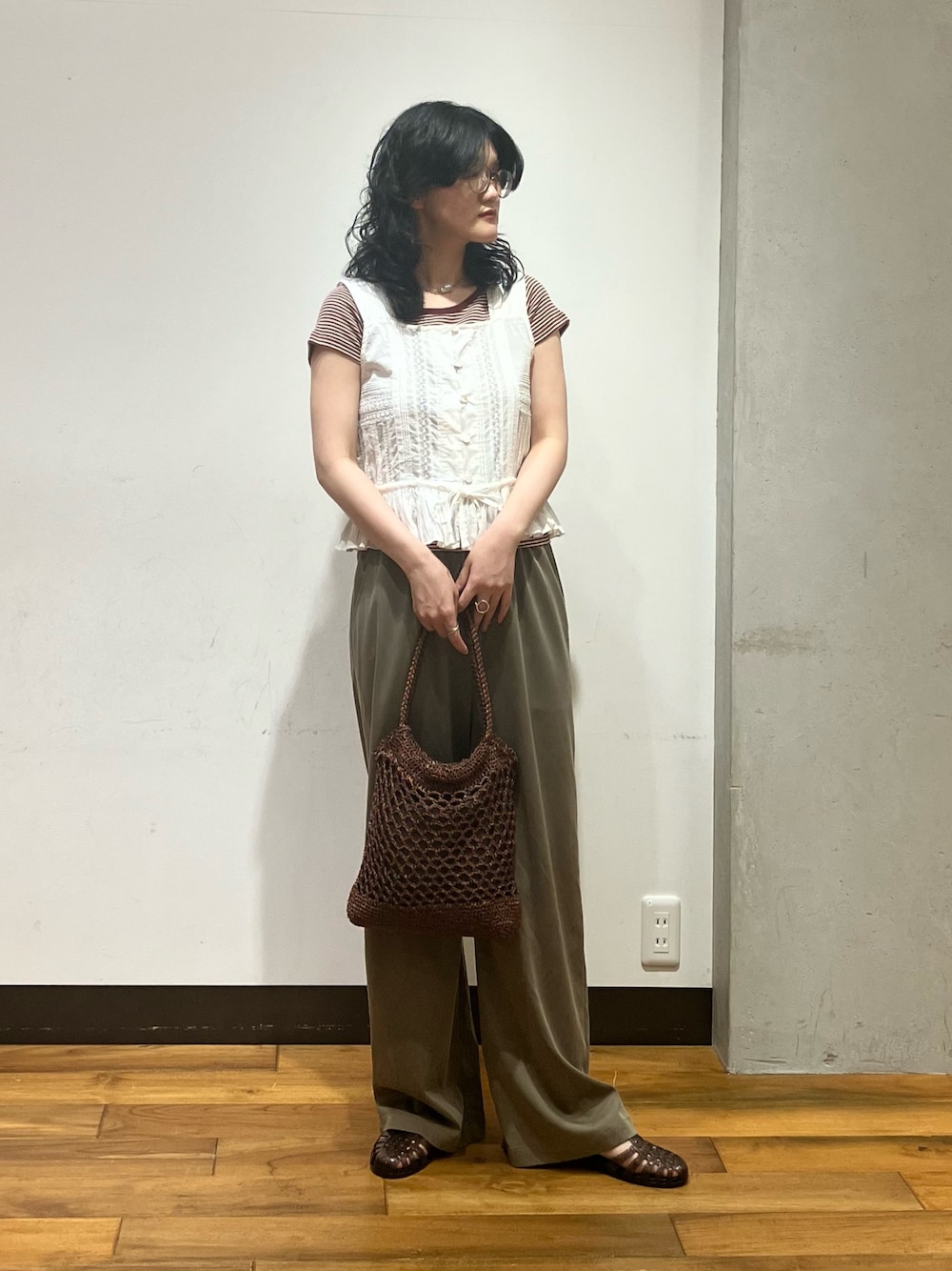 ブラウン系のトートバッグ、ホワイト系のシャツ/ブラウス、ブラウン系のTシャツ/カットソーを着用したレディースの夏コーディネートの1枚目の写真
