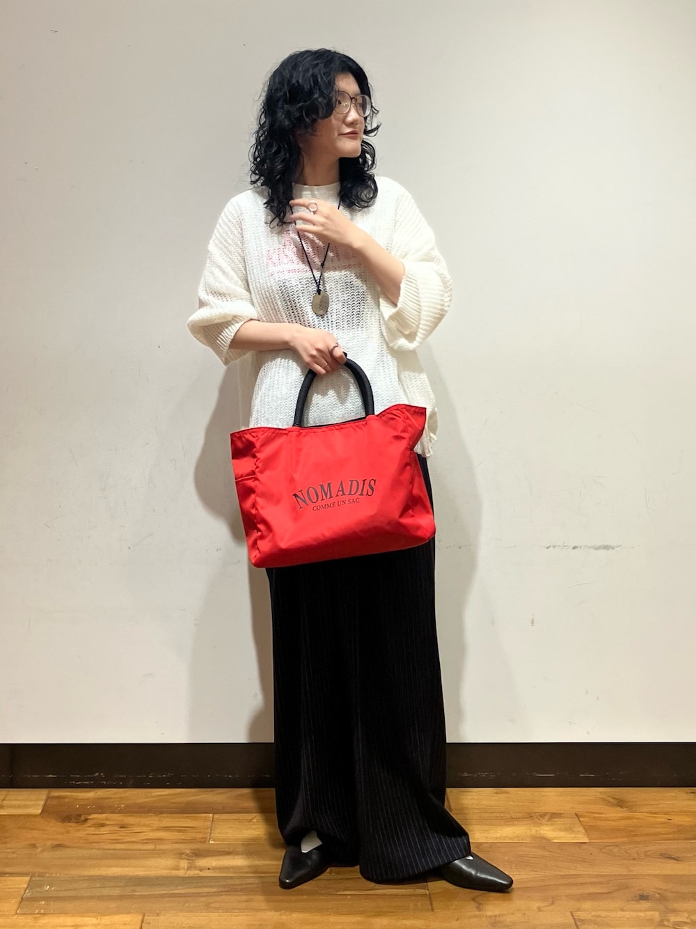 ホワイト系のニット/セーター、レッド系のトートバッグ、ホワイト系のTシャツ/カットソーを着用したレディースの秋コーディネートの1枚目の写真