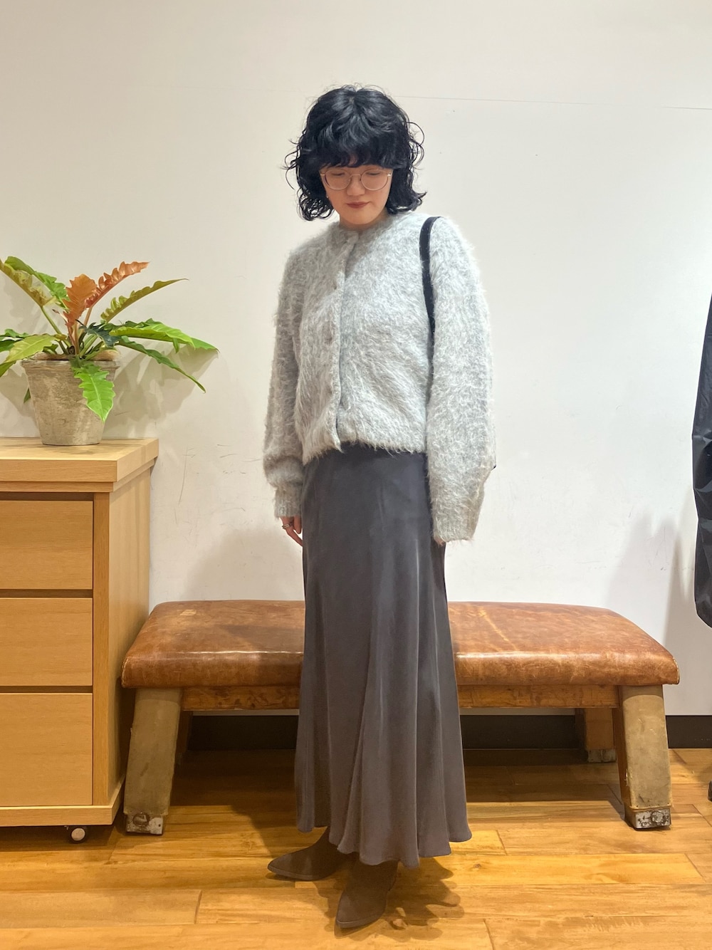 グレー系のスカート、グレー系のカーディガン/ボレロ、ブラック系のショルダーバッグを着用したレディースの秋コーディネートの1枚目の写真